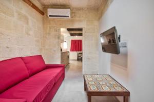 a living room with a red couch and a tv at Vallettastay Old Lodge Apartment 7 in Valletta