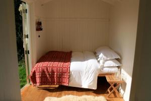 a bedroom with a bed with a red and white blanket at Snowdonia Shepherds' Huts in Conwy