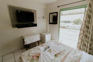 a bedroom with a bed and a tv and a window at Hotel Centro dos Canyons in Praia Grande