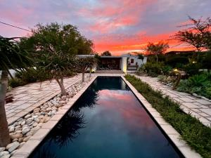 a swimming pool in a backyard with a sunset in the background at Chalcedony in McGregor