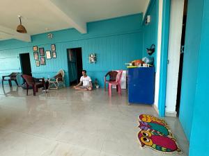 Ein Junge sitzt auf dem Boden in einem blauen Zimmer. in der Unterkunft Soul, Varkala - Black Beach in Varkala