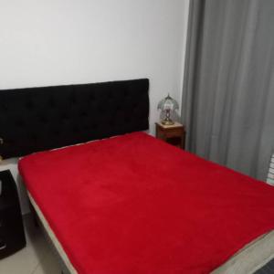 una manta roja en una cama en una habitación en Luxo sala e quarto quadra da praia Copacabana, en Río de Janeiro