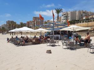 un gruppo di persone sedute sulla spiaggia sotto ombrelloni di Cosy 3-bedroom Duplex with pool close to the beach a El Campello