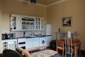 a kitchen with white cabinets and a table and a stove at townhouse apartments in Ayr