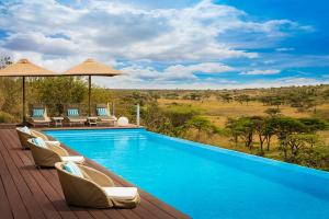 a swimming pool with chairs and umbrellas on a deck at Mahali Mzuri in Aitong