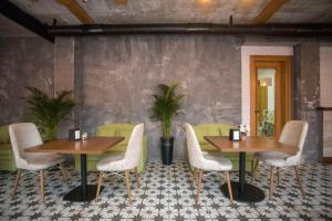 a restaurant with two tables and chairs and plants at Hotel London in Batumi