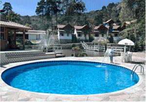 a large blue pool with a fountain in a yard at Pousada Chalés do Lago in Visconde De Maua