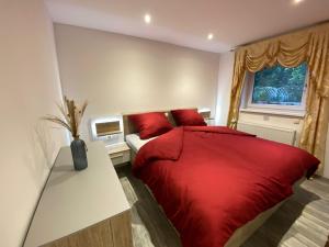 a bedroom with a red bed and a window at Ferienwohnung Gulfhaus, mit Sauna und großem Garten in Apen