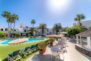 a resort with a pool and chairs and palm trees at Nazaret Sol in Costa Teguise
