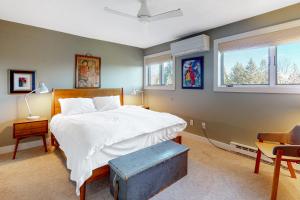 a bedroom with a bed and a chair and two windows at Saltbox 2A in Quechee