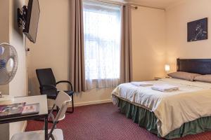 um quarto de hotel com uma cama, uma secretária e uma janela em City Centre Guest House em Gloucester