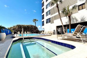 uma piscina em frente a um edifício com palmeiras em Arie Dam 401 em St. Pete Beach