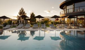 a pool with chairs and umbrellas next to a building at Hotel Chalet Mirabell in Avelengo