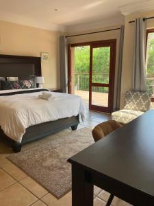 a bedroom with a bed and a table and a chair at 37 On Eagles in Hartbeespoort