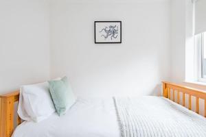 uma cama com almofadas brancas e uma fotografia na parede em The Heights em Kingsdown