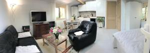 ein Wohnzimmer mit einem schwarzen Ledersessel und eine Küche in der Unterkunft Joli studio Les Hibiscus du Pic Saint Loup in Saint-Martin-de-Londres