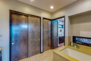 baño con puertas de madera, bañera y lavamanos en Riverbend Cabin #014, en Spicewood