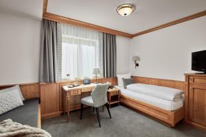 ザンクト・アントン・アム・アールベルクにあるHotel Gletscherblickのベッド、デスク、ベッド、ベッド、ベッドが備わるホテルルームです。
