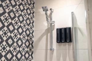 a shower in a bathroom with black and white tiles at OLD LISTING Cardiff Bay, Modern Chic 2BR, Free Parking in Cardiff