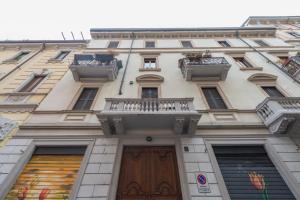 ein hohes Gebäude mit einem Balkon und einer Holztür in der Unterkunft Heart Centre Milan Navigli 3 Levels Apartment in Mailand