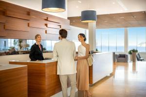 a man and woman standing at a counter in an office at Dubrovnik President Valamar Collection Hotel in Dubrovnik