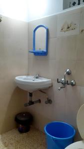 a bathroom with a sink and a blue bucket at Oasis Beach Resort in Agonda