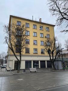 ein gelbes Gebäude mit einer Bank davor in der Unterkunft Daukanto 5 in Kaunas