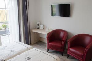 a room with two chairs and a desk with a tv at Wil's Bed & Breakfast in Zoutelande