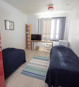 a bedroom with two beds and a desk with a television at Majatalo Jurtta in Rautuskylä