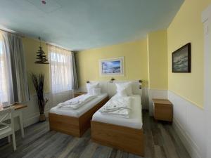 two beds in a room with yellow walls at HOTEL Bahnhof Balingen in Balingen