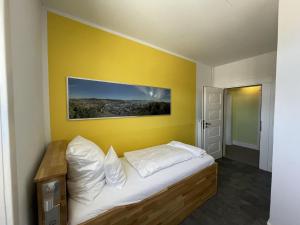 a bedroom with a bed with a yellow wall at HOTEL Bahnhof Balingen in Balingen