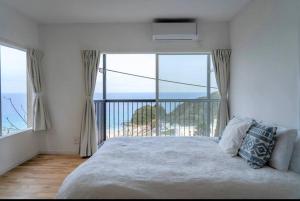 a bedroom with a bed with a view of the ocean at Sirahama Beach House in Shimoda