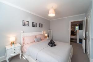 a bedroom with a white bed and a white nightstand at A beautiful and stylish 2 bed flat close to beach in Bournemouth