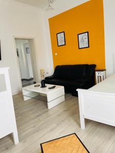 sala de estar con sofá negro y pared amarilla en City Pension Bremerhaven, en Bremerhaven
