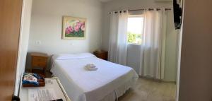 1 dormitorio con cama blanca y ventana en Casarão Hotel, en Brotas