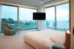 a bedroom with a bed and a chair and large windows at Mythical Villas Zeus and Venus in Protaras