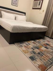 een slaapkamer met een bed met een tapijt op de vloer bij هوتيل حايل للشقق المفروشة يتوفر شهري سنوي in Hail