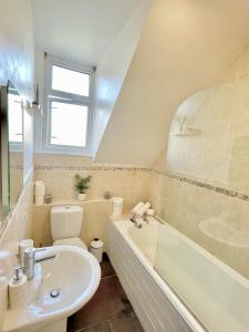 uma casa de banho com um lavatório, uma banheira e um WC. em Four Oaks em Bournemouth