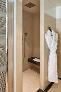 a bathroom with a shower with a robe on a wall at Maison Albar - Le Pont-Neuf in Paris