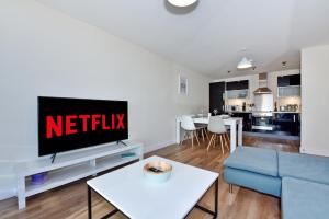 sala de estar con TV y sofá azul en The Vizion serviced apartments from Pincott Properties - free parking, private balcony, and WiFi, en Milton Keynes