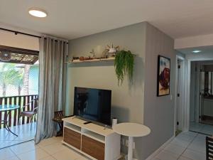 a living room with a flat screen tv and a table at Apartamento Na Praia De Itacimirim in Itacimirim
