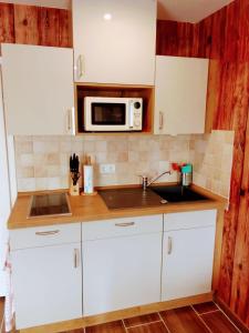 a kitchen with white cabinets and a microwave at Pension am Reethaus in Komptendorf