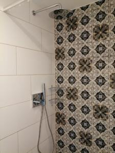a shower in a bathroom with a tile wall at Pension am Reethaus in Komptendorf