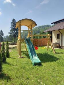 a playground with a green slide and a gazebo at Cabana Ioana in Voronet