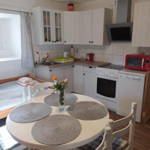 eine Küche mit einem Tisch mit 2 Stühlen und eine Küche mit weißen Schränken in der Unterkunft Apartmán Dvorečná in Loučovice