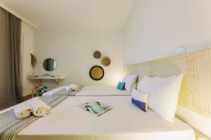 a bedroom with a bed with white sheets and pillows at Mikra Bay Vineyard Guesthouses in Naxos Chora