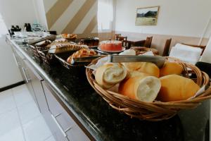 a buffet with a basket of bread on a counter at Hotel Centro dos Canyons in Praia Grande +40 photos