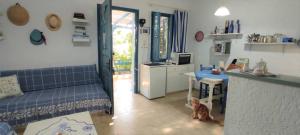 a living room with a blue couch and a kitchen at A Cretan house in a garden,overlooking the sea. in Ierapetra