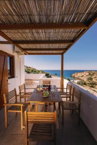 een houten tafel en stoelen op een balkon met uitzicht op de oceaan bij Mikra Bay Vineyard Guesthouses in Naxos Chora