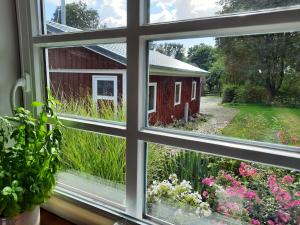 ein Fenster mit Blick auf eine rote Scheune in der Unterkunft Idyllisches Schwedenhaus in ruhiger Hanglage in Oetzen